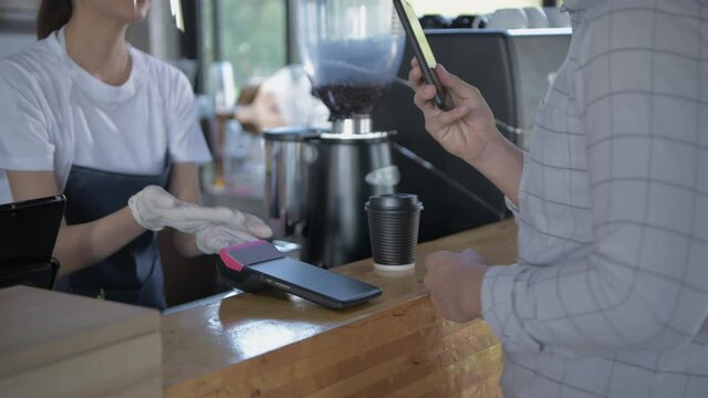 Coffee shop concept of 4k Resolution. The employee is handing the payment machine to the customer for scanning.