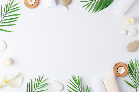 Spa treatment with towel, candles and palm on white background. Flat lay, copy space.
