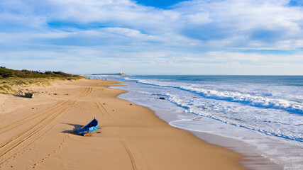 Immigrant and refugee dinghy boat stranded on the shore of a bautiful sand beach in south Spain....