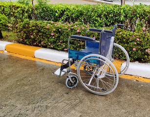 Handicapped wheelchair on the side of the footpath, white and yellow in the rain