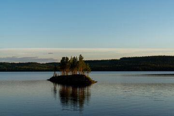 idyllic lake landscape with a small island with trees under a cloudless blue sky
