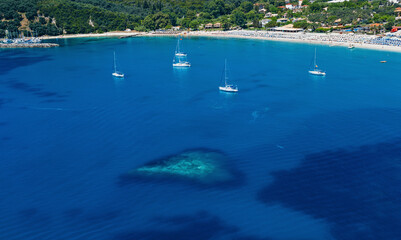 Fototapeta na wymiar Mediterranean deep blue sea bay with heart shaped shallow water, sailing yachts and sandy coastline
