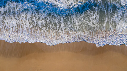 Aerial top view of shore waves washing the sand of the beach in Andalusia, Spain. Spanish sand...