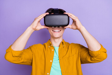 Photo of young man happy positive smile hands touch virtual reality glasses vr game isolated over violet color background