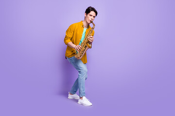 Full length photo of young man happy positive smile play sax jazz artist isolated over violet color background