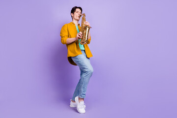 Full size photo of joyful brunet young guy play saxophone wear shirt jeans isolated on violet color...