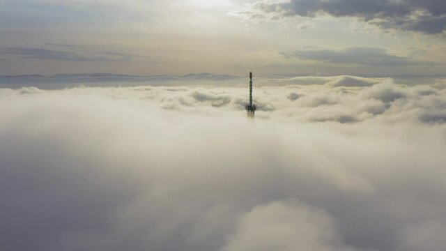 Aerial view of the upper part of the broadcasting tower in the fog