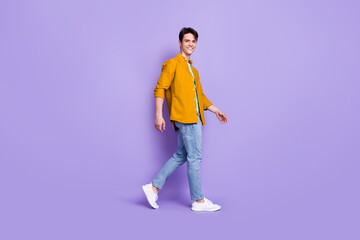 Naklejka premium Full size profile side photo of young man happy positive smile go walk step meeting isolated over violet color background