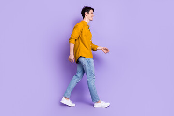 Fototapeta premium Full size profile photo of friendly brunet young guy go wear shirt jeans isolated on violet color background