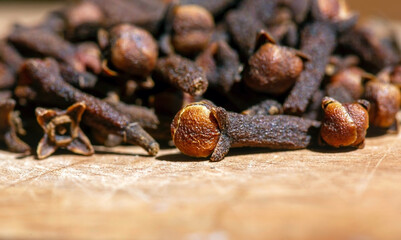 Dried clove seeds, in shallow focus, on the natural wooden table