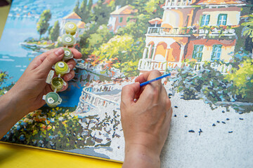Painting for beginners, a woman draws a picture by numbers with acrylic paints on canvas artist...