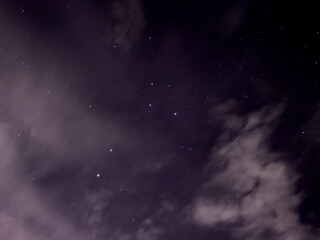 Fototapeta na wymiar Southern Cross star formation on a cloudy night with light pollution causing a slight haze and slow shutter speed causing the clouds to blur.