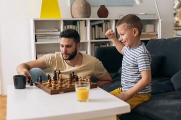 father and son playing chess at home