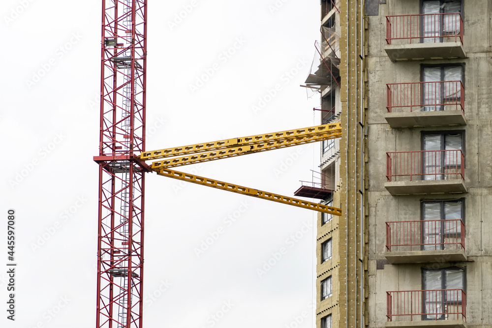 Poster view of frame part of metallic crane machinery attachment at windows of new residential building con