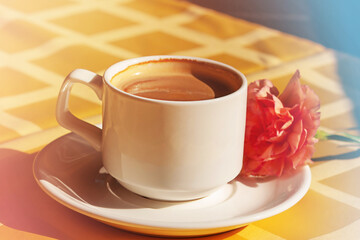 cup of coffee. Cup of coffee with milk in a white cup in the morning. Carnation flower on a saucer.