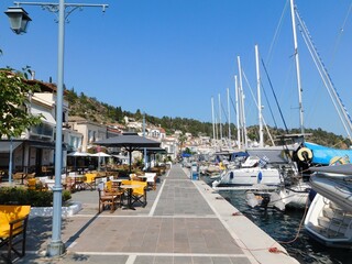 A seaside street with restaurants, traditional houses and boats, in the island’s town, at Poros,...