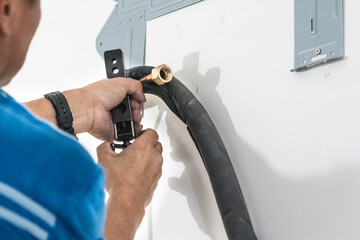 Technician installing indoor air conditioner compressor condenser copper pipe on wall