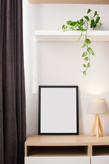 Empty photography frame mock up with wooden lamp and lush plant on shelf. Template for pictures, photos. Home interior, domestic room in black and white colors with wooden elements and flower. - obrazy, fototapety, plakaty