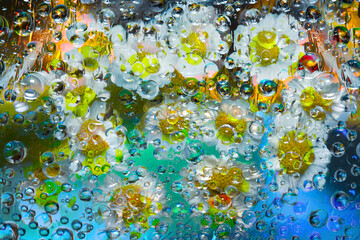 Transparent raindrops falling down against the turquoise-gold background with silhouettes of...