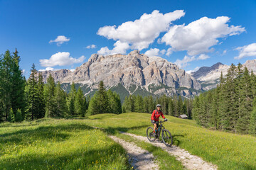 nice and active senior woman riding her electric mountain bike on the Pralongia Plateau in the Alta...