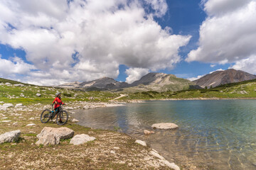 Fototapeta premium pretty active senior woman riding her electric mountain bike at Lago de in the Fanes high Valley, part of Fanes-Sennes-Braies nature park in the Alta Badia Dolomites, South Tirol and Trentino, Italy 