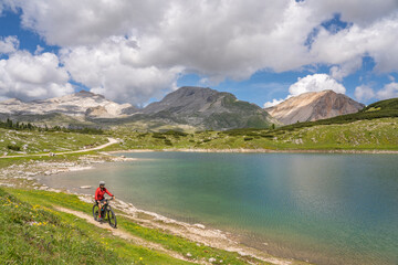 pretty active senior woman riding her electric mountain bike at Lago de in the Fanes high Valley, part of Fanes-Sennes-Braies nature park in the Alta Badia Dolomites,  South Tirol and Trentino, Italy

