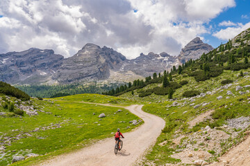 Fototapeta na wymiar pretty active senior woman riding her electric mountain bike in the Fanes high Valley, part of Fanes-Sennes-Braies nature park in the Alta Badia Dolomites, South Tirol and Trentino, Italy 