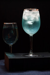 This sparkling blue,sweet flavored, transparent,fizzy hawaiin mocktail is perfect drink for summer. Garnished with fresh lime,ice cubes close view has book as dark background and condensation on glass