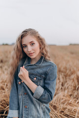 a beautiful girl with long brown hair in a field with ears of wheat