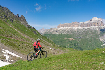 Fototapeta premium pretty active senior woman riding the famous Sella Ronda mountain bike Trail in Sella mountain group, Dolomites of Selva Wolkenstein, Val Gardena, South Tirol and Trentino, Italy