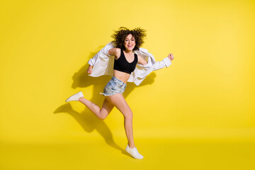 Photo of pretty shiny young lady wear black top smiling jumping running fast isolated yellow color background