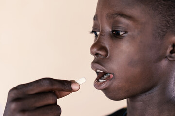 Young African ethnicity boy taking an oral medication from a black health professional