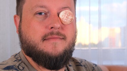 man holds bitcoins. Male with bitcoin in eye. Bitcoin is a cryptocurrency invented in 2008 by an...