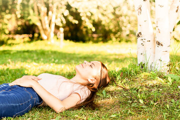 Naklejka na ściany i meble happy teenager is lying on the grass, smiling, laughing, summer holidays and weekends in the park
