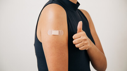 woman vaccinated and with a band-aid on her arm, giving a sign that all is well.