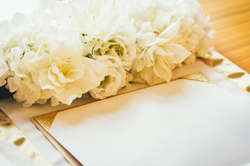 Blank certificate decorated with white flowers on wooden desktop