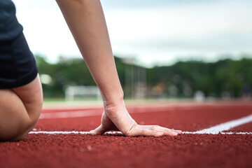 Action of a runner is placing hand on starting position of running racetrack, ready to start. Sport...