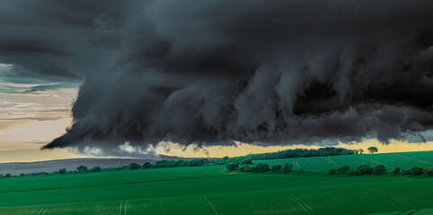 Green field with thunderous black clouds hanging low over it just before a tornado