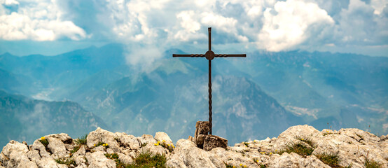 Gipfelkreuz vor den italienischen Alpen.