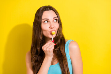Photo portrait girl in blue singlet smiling eating lollipop looking copyspace isolated vivid yellow...