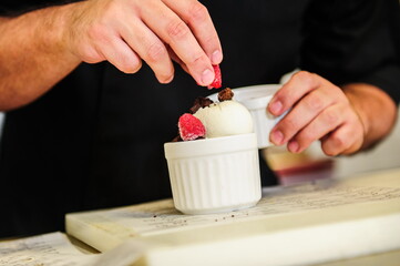 Cheef's hands decorating ise cream with berry