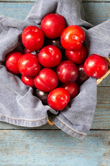 Chinese or Korean red plum in a basket on the table top view Summer or autumn harvest