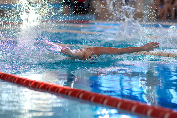 a swimmer waves his arms while performing a butterfly at a training session in the pool, blurred focus