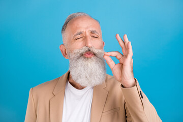 Portrait of handsome classy dreamy grey-haired man tasting good food cigarette isolated over bright blue color background