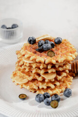 a stack of waffles with blueberries and honey
