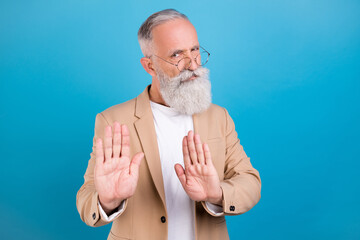 Portrait of attractive serious grey-haired man showing stop sign dislike isolated over bright blue...