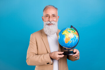 Portrait of handsome cheerful grey-haired man holding globe knowledge tutor isolated over bright blue color background