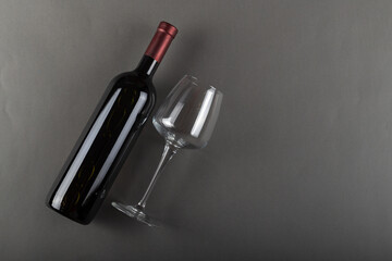Naklejka premium Corked bottle of red wine and empty wine glass on gray background. Alcoholic drink. Winemaking concept. Space for text.