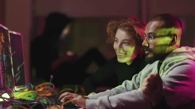 Group of modern malefactors spending time together late at night successfully finishing hacking security information