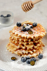 a stack of waffles with blueberries and honey